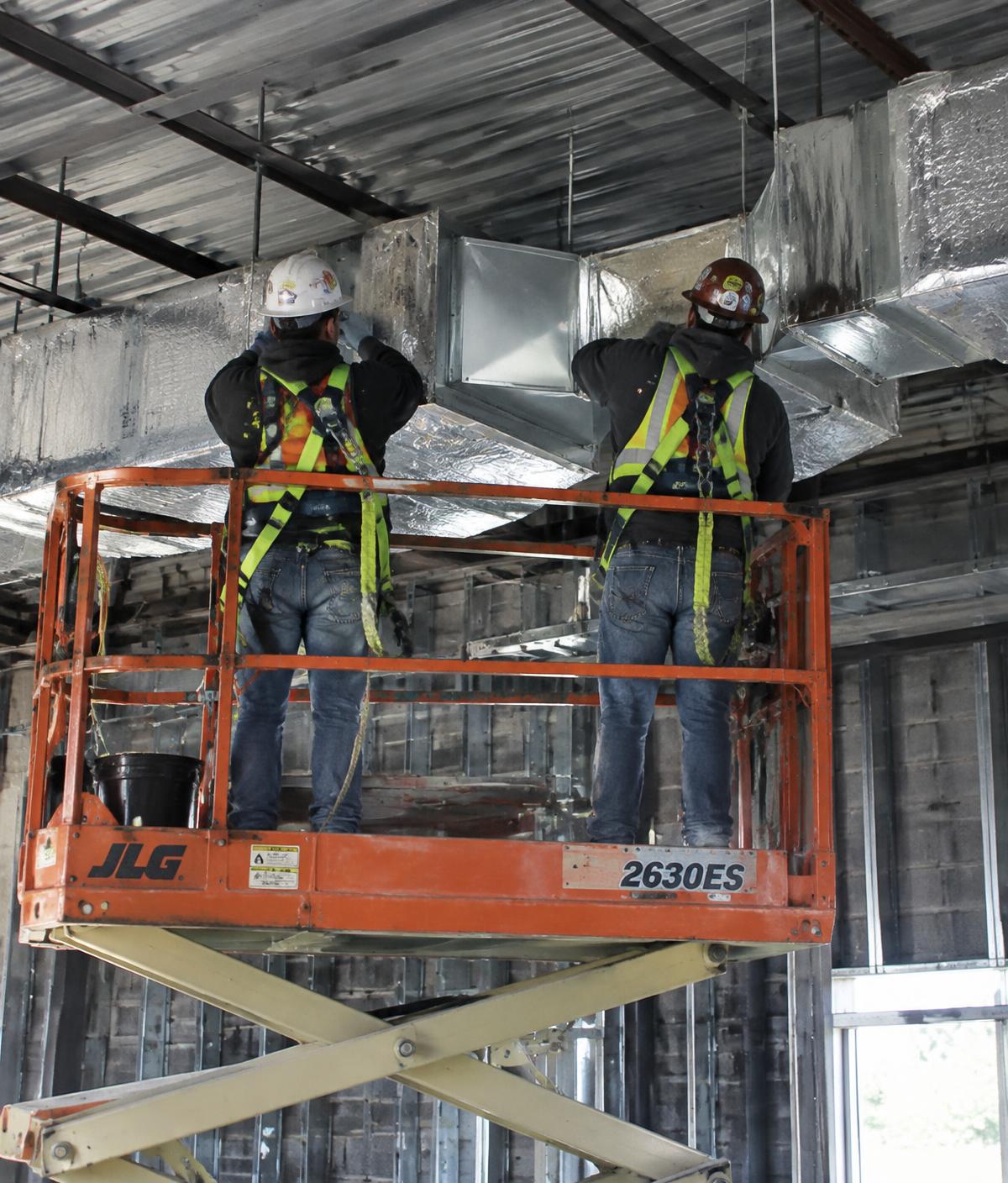 Equipe realizando montagem de dutos isolados em obra